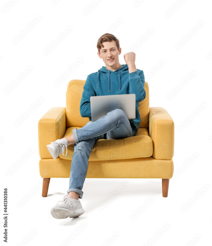 Happy young man with laptop sitting in armchair on white background