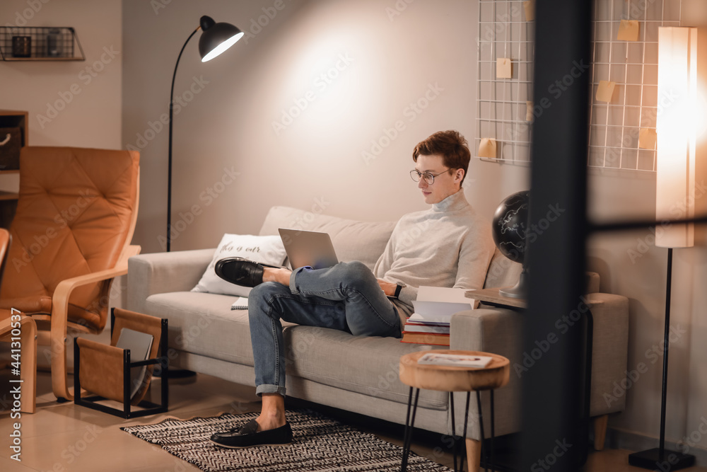 Young man studying online at home in evening