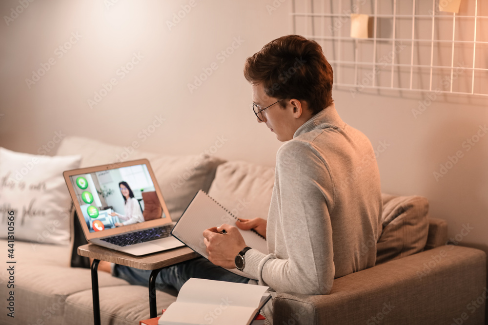Obraz premium Young man studying online at home in evening