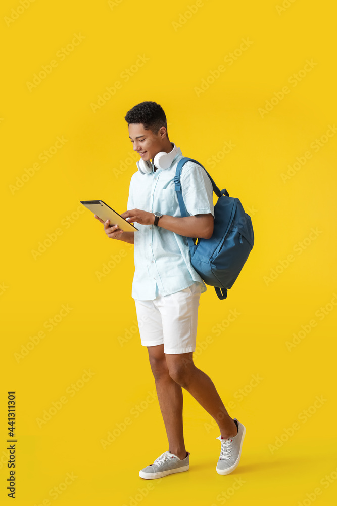 Male African-American student with tablet computer on color background Male African-American student with tablet computer on color background