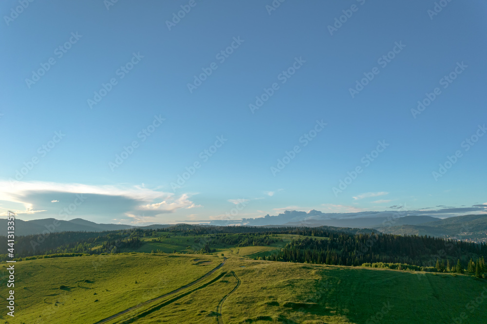 AERIAL: panorama of a forest valley with fields in the mountains. beautiful landscape with clean forest and meadows in early summer