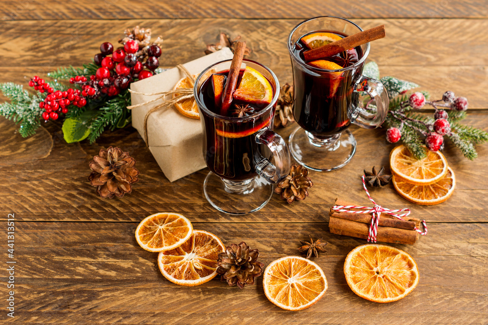 Mulled red wine with spices. Christmas decoration with dried orange slices. cinnamon sticks and christmas presents on wooden background