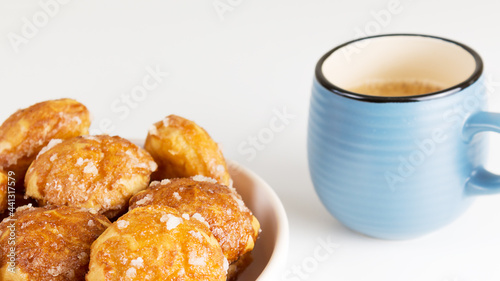 french chouquettes puffs with perles of sugar on plate with blue cup of coffee. Choux pastry Classic French bakeries. 