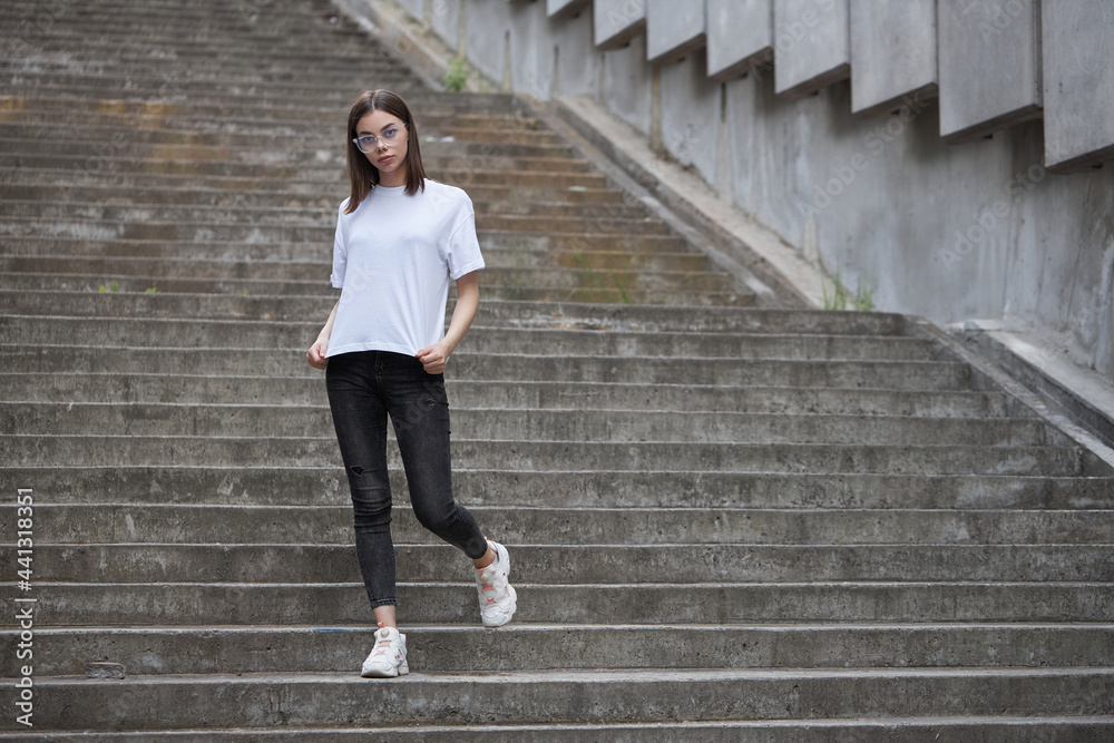 Girl or woman wearing white blank t-shirt with space for your logo, mock up or design in casual urban style Girl or woman wearing white blank t-shirt with space for your logo, mock up or design in casual urban style
