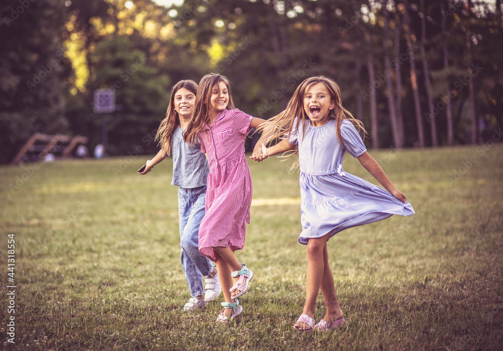 Three smiling little girls running trough nature and holding hands. Three smiling little girls running trough nature and holding hands.