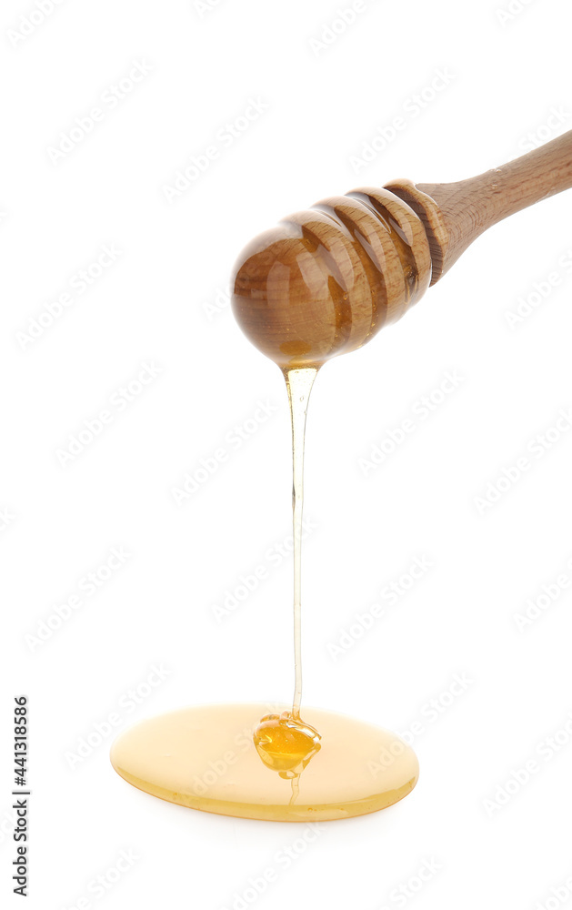 Honey pouring from wooden dipper on white background