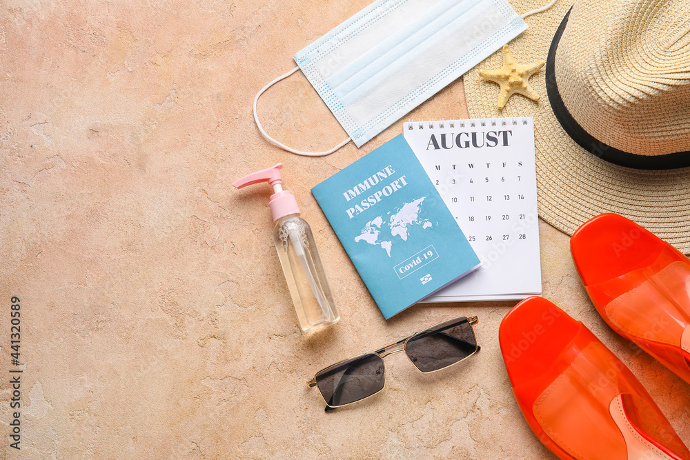 Calendar with beach accessories, medical mask and immune passport on color background Calendar with beach accessories, medical mask and immune passport on color background