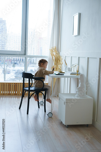 маленькая девочка в светлой домашней одежде сидит за белым столом рисует © Юлия Михайлова