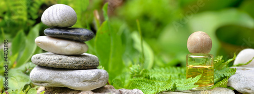 essential oil bottle next to a pile of  pebbles among green foliage in garden