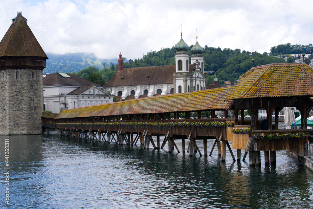 Famous wooden Kappelbrücke (Chapel Bridge) at the old town of Lucerne with medieval stone water tower with wooden roof. Photo taken June 22nd, 2021, Luzern, Switzerland.