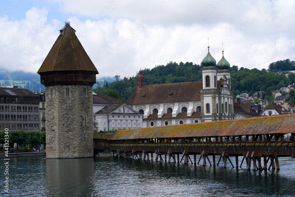 Famous wooden Kappelbrücke (Chapel Bridge) at the old town of Lucerne with medieval stone water tower with wooden roof. Photo taken June 22nd, 2021, Luzern, Switzerland.