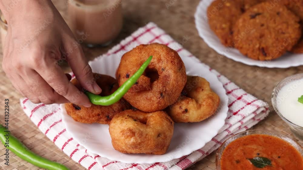 Medu Vada with tiffin sambar coconut chutney in traditional background , savory fried tea time snack of Kerala, Tamil Nadu South India.  Indian veg breakfast food 4K slow motion video footage.