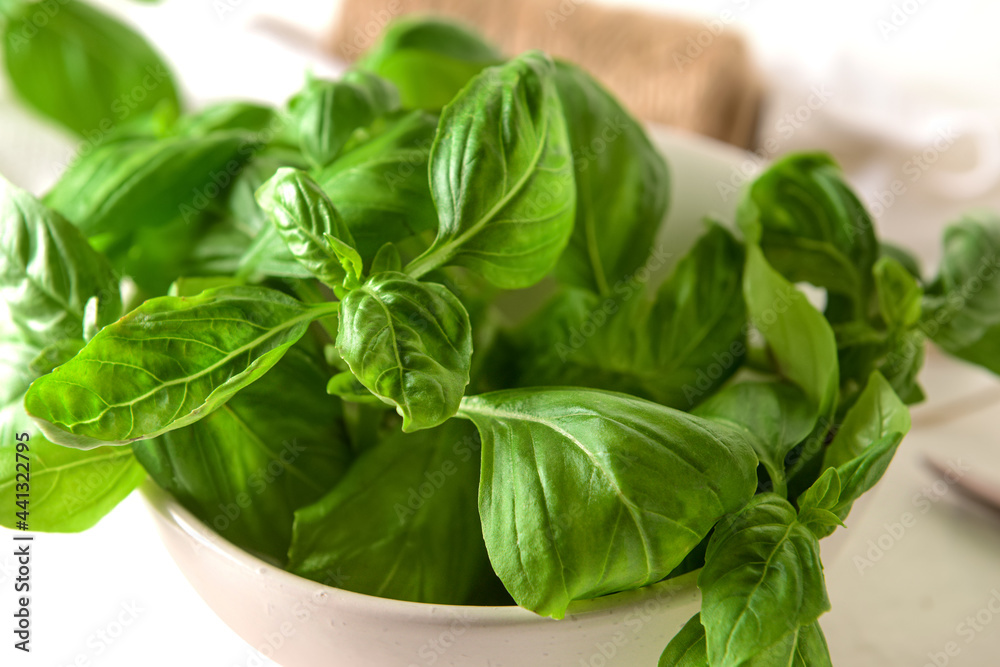 Bowl with fresh basil leaves on table, closeup Bowl with fresh basil leaves on table, closeup