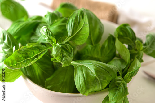Bowl with fresh basil leaves on table, closeup