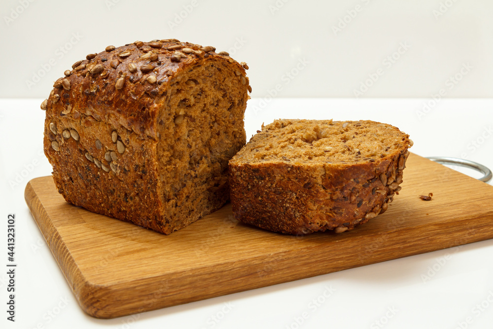 Cut loaf of bread on wooden cutting board on white background Cut loaf of bread on wooden cutting board on white background
