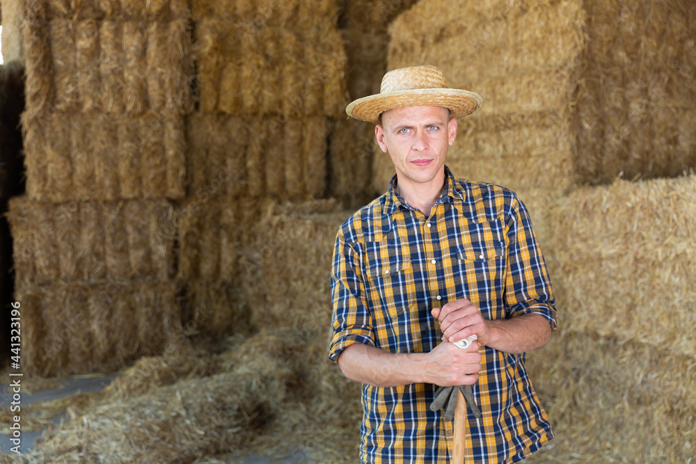 Cow farm owner posing in the barn against the backdrop of hay bales