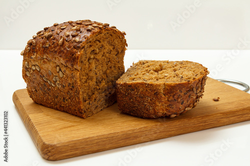 Cut loaf of bread on wooden cutting board on white background