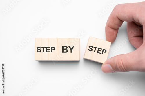 The word step by step on wooden cubes. Achievement or progress in business career.