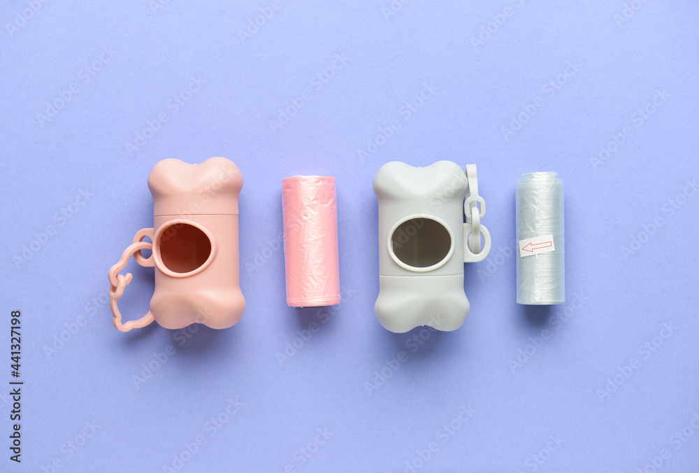 Dispensers with pet waste bags on color background