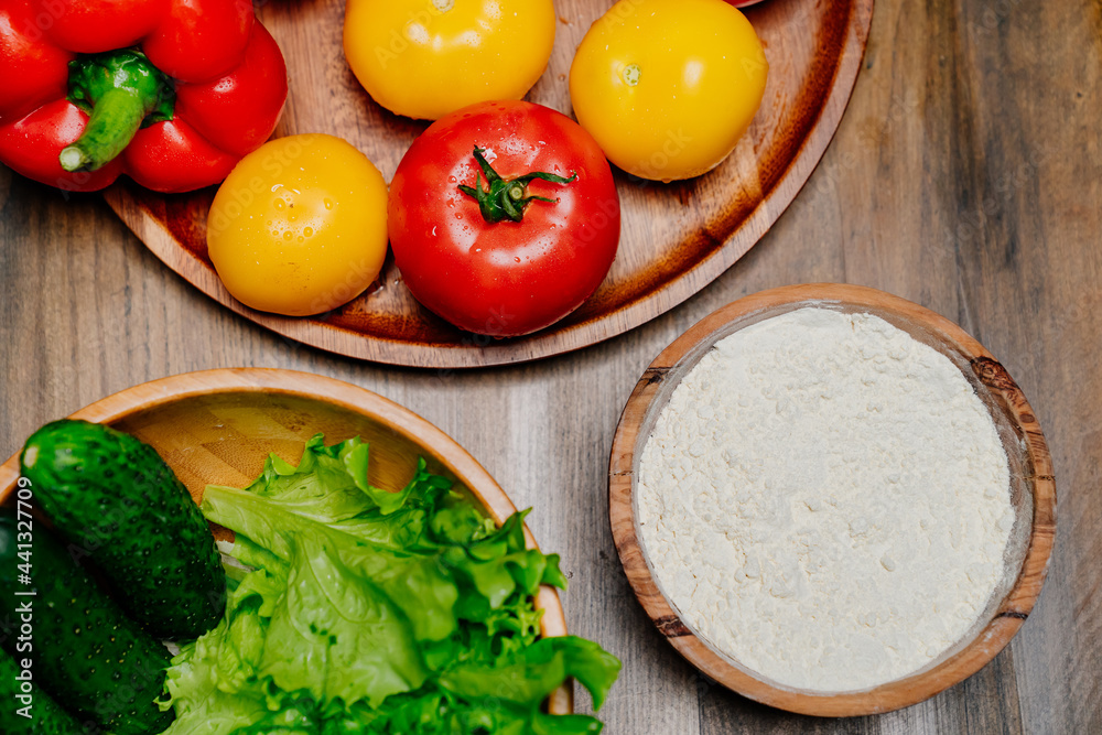 top view. a wooden utensil with flour and vegetables on the kitchen table. top view. a wooden utensil with flour and vegetables on the kitchen table.