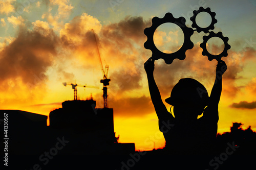 Silhouette of happy father and son wearing construction hats holding cogs showing evening industrial business drive. innovative process concept Teamwork, strategy, creativity in industrial cooperation