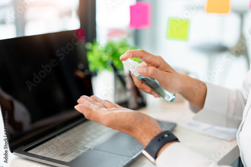 a male freelancer using alcohol rubbing his hands preventing the germ while working with others photo