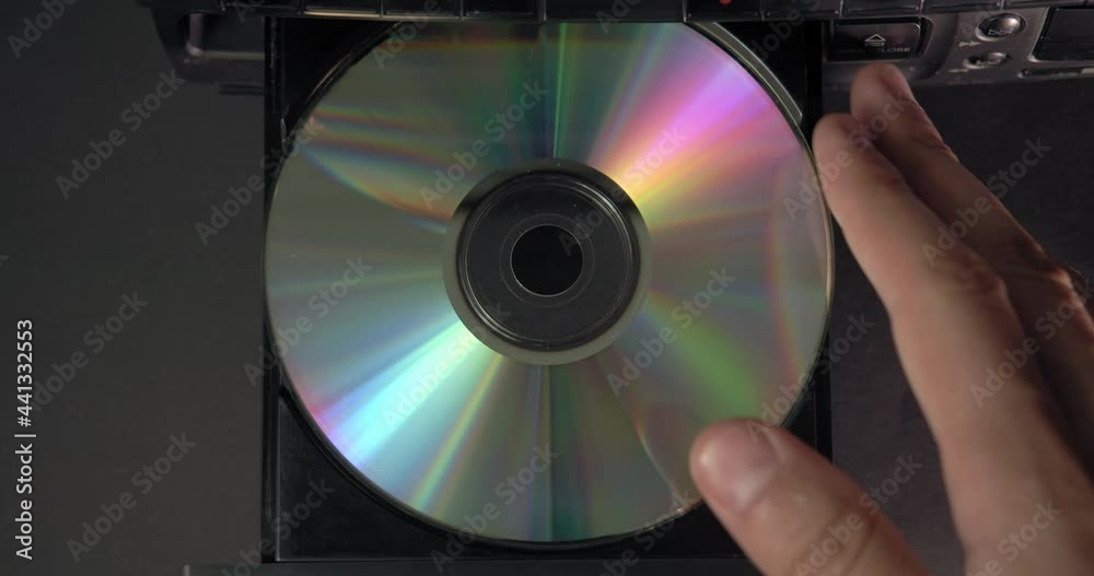 A hand inserts a CD into the player. Music or data recorded on a laser compact disc. A hand inserts a CD into the player. Music or data recorded on a laser compact disc.