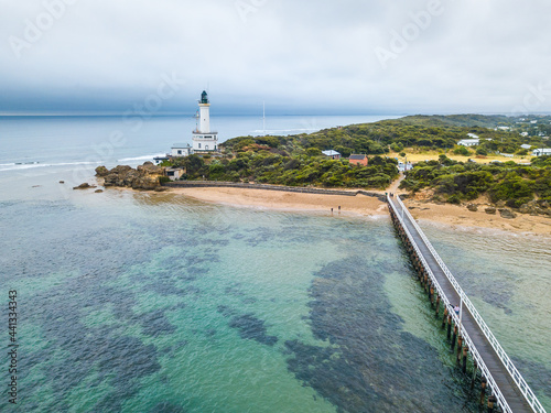 Aerial view of a jetty leading to a lighthouse on a coastline photo