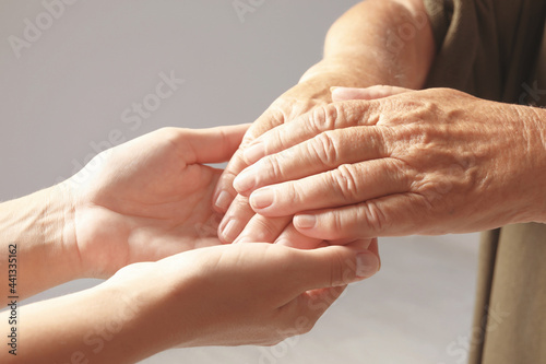 Helping hands on grey background, closeup. Elderly care concept
