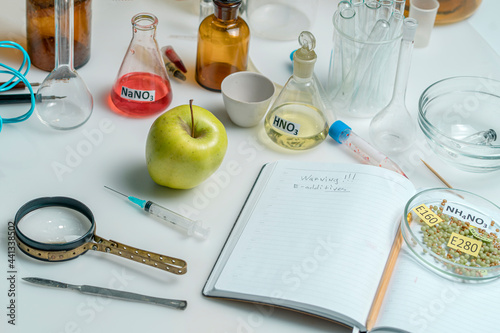 Food saferty lab. View of fresh ripe apple with test tubes and tools on table in research lab. Concept of genetic modification of fruits. photo