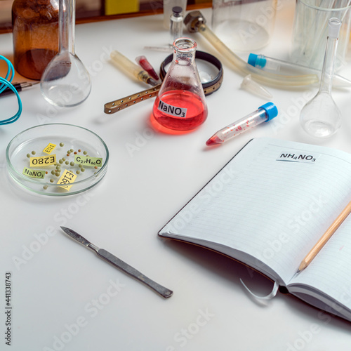 Food safety laboratory. View of a fresh ripe apple with test tubes and tools on a table with an open notepad in a research laboratory. The concept of genetic modification of fruits.