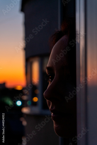a beautiful girl watches the sunset from the balcony