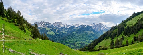 View on alps mountains, cloudy sky, green fields by Jaun,  kanton Fribourg, Freiburg nearby Bulle, Bern, Thun. Good hiking tourist way. Switzerland.