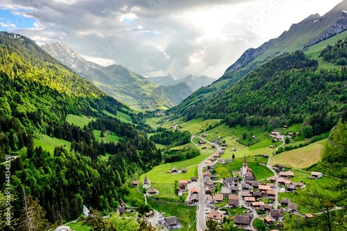 View on alps mountains, green fields, cloudy sky, Church by Jaun,  Jaunpass. Canton Fribourg, Freiburg nearby Bulle, Bern, Thun. Good hiking tourist way. Switzerland.