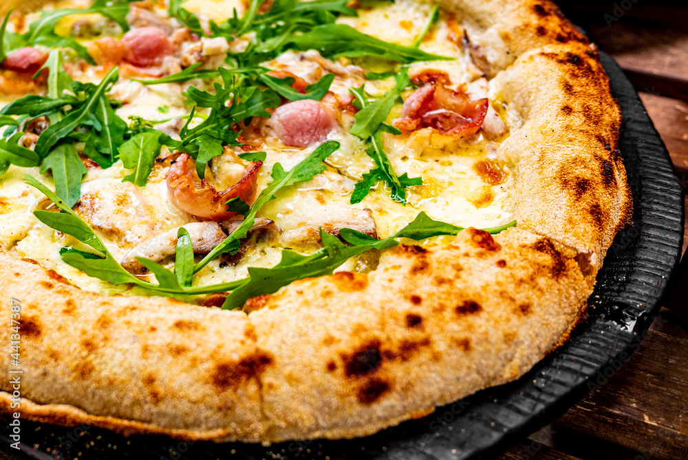 Pizza with Mozzarella cheese, mushrooms, ham, tomato sauce, pepper, Spices and Fresh arugula. Italian pizza on wooden table background Pizza with Mozzarella cheese, mushrooms, ham, tomato sauce, pepper, Spices and Fresh arugula. Italian pizza on wooden table background