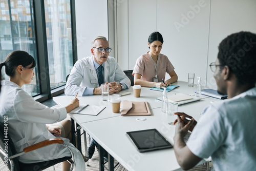 High angle view at diverse group of doctors sitting at meeting table in conference room during medical seminar, copy space
