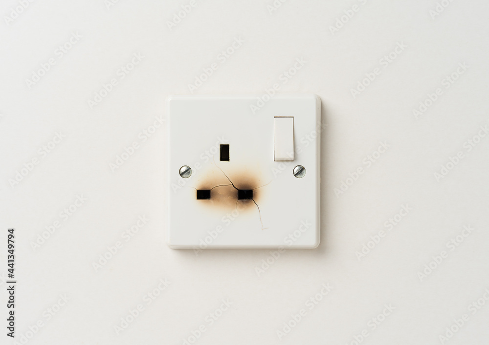 Broken electrical domestic power socket with cracks and burn marks on a white wall Broken electrical domestic power socket with cracks and burn marks on a white wall