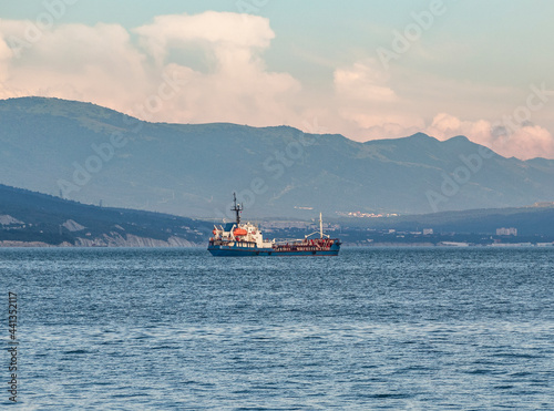 Fuel tanker or bunker ship sailing on water at mountains background photo