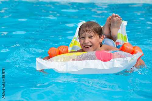 Принти на полотні A happy child safely swims in the pool on an air mattress and in armbands