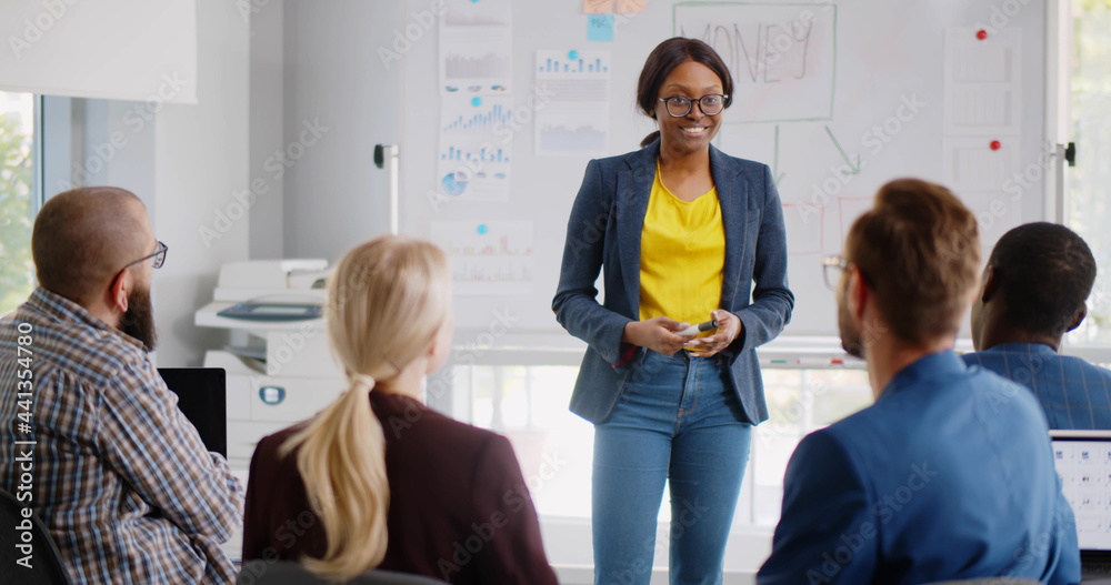© TommyStockProject - Female african business trainer explaining project data to interns © TommyStockProject - Female african business trainer explaining project data to interns