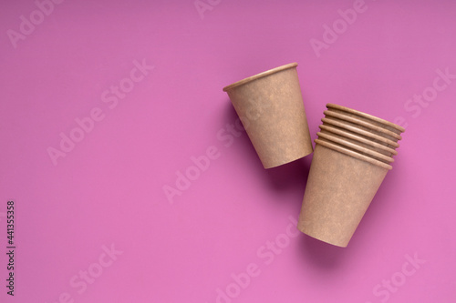 Top view of reusable paper cup on the bright pink surface.Empty space