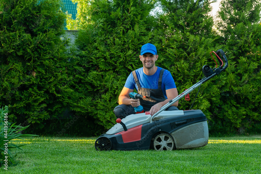 Fototapeta premium A professional repairman repairs a lawn mower, a man repairs a mower in his backyard
