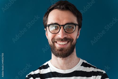 Positive, smiling man in eyeglasses on a blue background. Beautiful brunette isolated on blue background © speed300