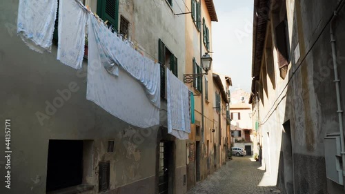 Beautiful narrow street in an ancient village Tuscania of Viterbo province, amazing medieval atmospheric mood with building exterior and hanging laundry outdoors. Italian culture, villages of heritage