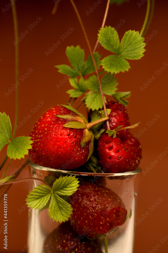 Strawberry close-up. Lettuce leaves and strawberry mustache. Brown background. Berries in a glass. Strawberry close-up. Lettuce leaves and strawberry mustache. Brown background. Berries in a glass.