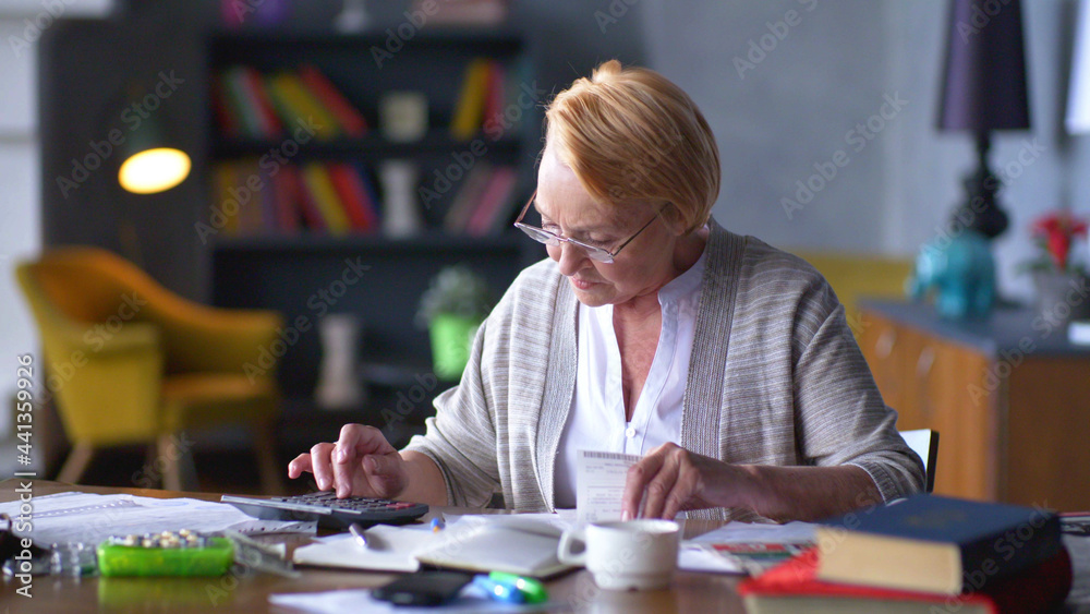 Senior business woman holding paper bill using calculator