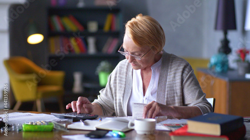 Senior business woman holding paper bill using calculator