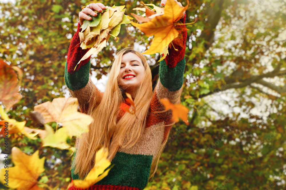Joyful girl throws leaves in autumn park. Woman feel good outdoors in fall. Happy smiling person in nature background Joyful girl throws leaves in autumn park. Woman feel good outdoors in fall. Happy smiling person in nature background