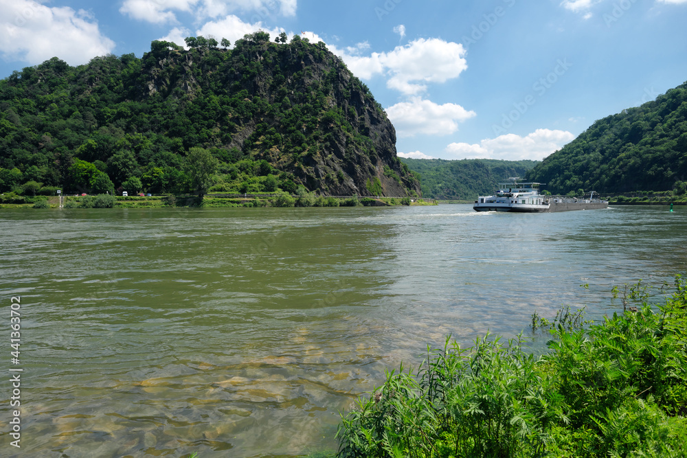 Der Rhein mit Untiefe am Flussufer am Felsen der Loreley im Welterbe Oberes Mittelrheintal und Tankschiff und strahlend blauer Himmel - Stockfoto
