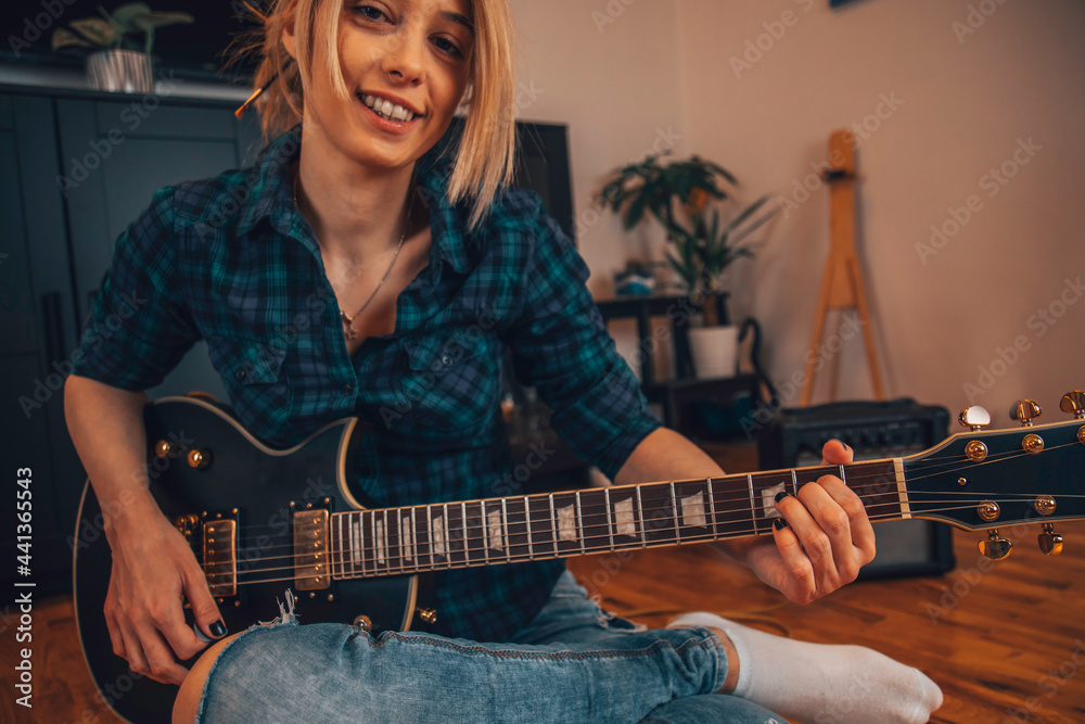 Obraz premium A modern woman play guitar at home.
